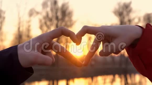 一个男人和一个女孩在光明的背景下以一颗心的形状一种爱的象征握住他们的手视频的预览图