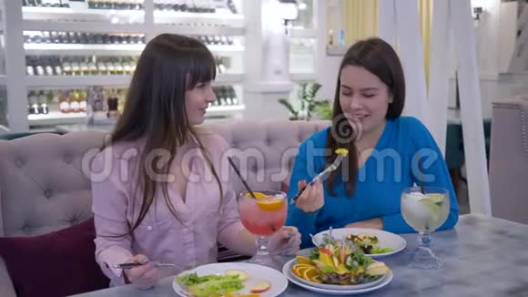适当的营养女朋友在节食期间吃水果在咖啡馆坐在桌边喝新鲜果汁视频的预览图