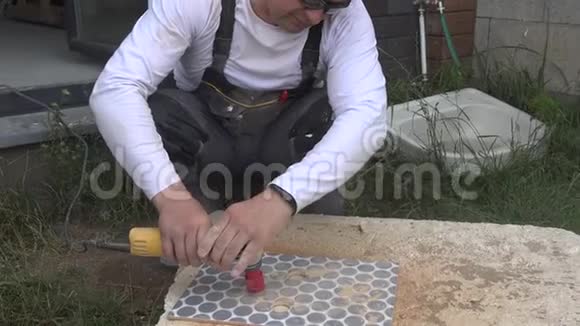熟练的人用镶钻的角磨机切割瓷砖上的孔视频的预览图