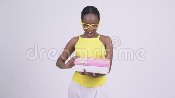 快乐年轻美丽的非洲女人打开礼盒看上去很惊讶视频的预览图