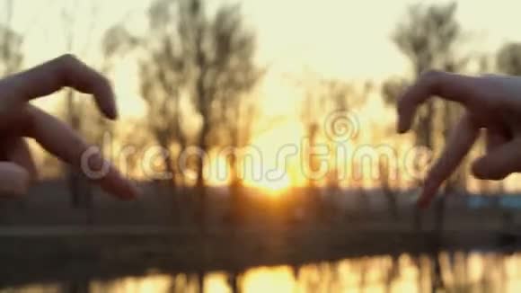 一对相爱的情侣在明黄的夕阳下用心形的双手相接透过太阳看视频的预览图