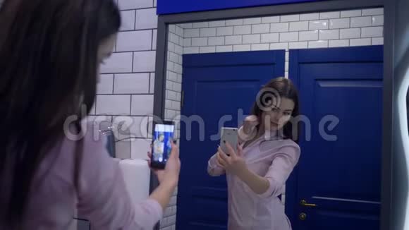 在博客上年轻女子用手机记录下站在厕所镜子前的视频视频的预览图