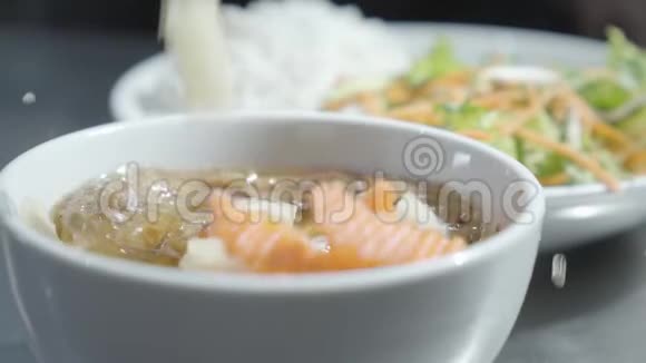 厨师把胡萝卜和洋葱放在碗里站在模糊的面条和维生素沙拉的前面这就是视频的预览图