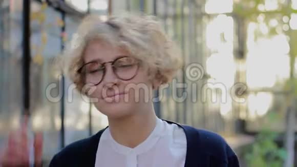戴着眼镜看着相机摘下眼镜的幸福金发女人的肖像视频的预览图