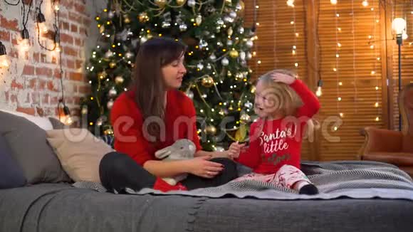 小女孩和妈妈在圣诞树附近吃糖果视频的预览图