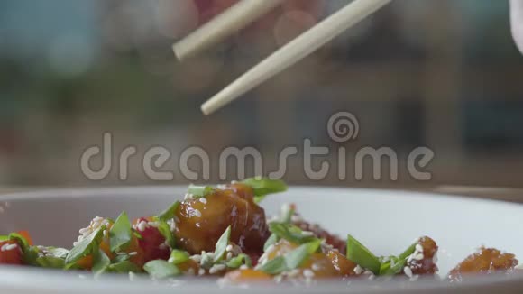 这只手用筷子近距离地从盘子里取出美味的蜂蜜鸡肉中餐厅晚餐视频的预览图