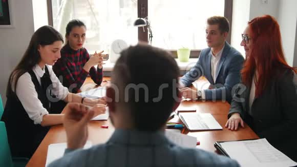 商业概念一位主管坐在会议上一边拿着文件一边和下属交谈视频的预览图