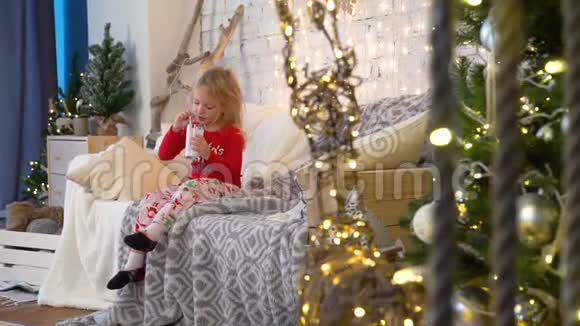 小女孩在圣诞树附近喝奶昔视频的预览图