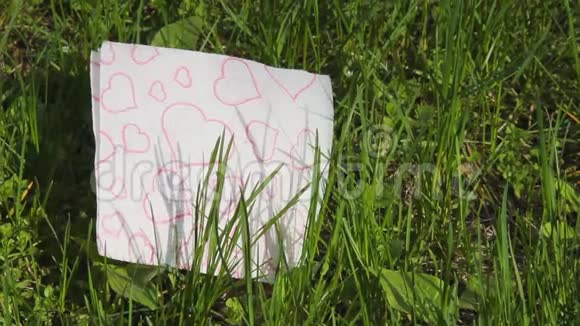 一张红心的白色餐巾躺在新鲜的绿草上春爱的概念情人节象征性的四月自然醒了你好视频的预览图