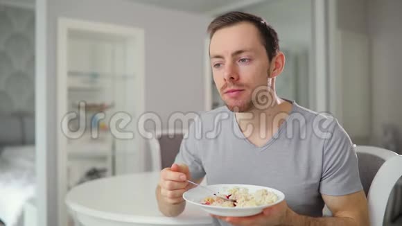 年轻人吃着美味的早餐在家里兴高采烈地竖起大拇指视频的预览图