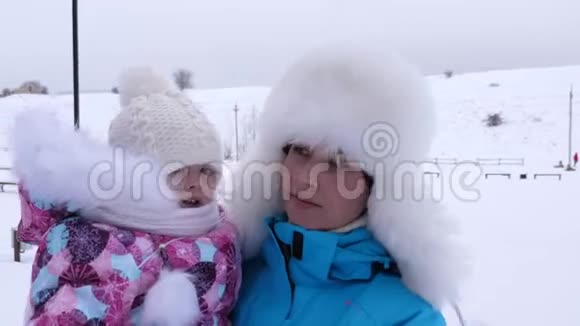 在寒冷的冬天我妈妈手里的宝贝在白雪上散步母亲带着孩子在大自然中散步圣诞节视频的预览图