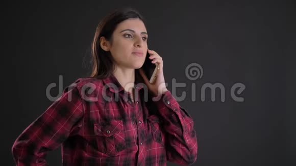 年轻美丽的白种人长发女孩在黑色背景下专心地用手机说话的肖像视频的预览图