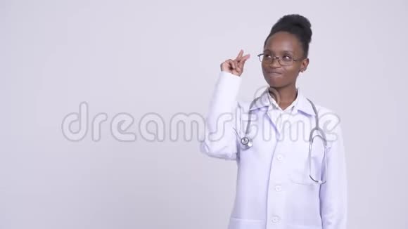 年轻快乐的非洲女医生一边思考一边指出视频的预览图