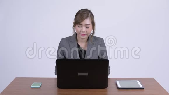 年轻快乐的亚洲女商人在工作中使用笔记本电脑思考视频的预览图