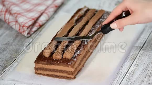 女人手把巧克力奶油撒在巧克力海绵蛋糕上视频的预览图