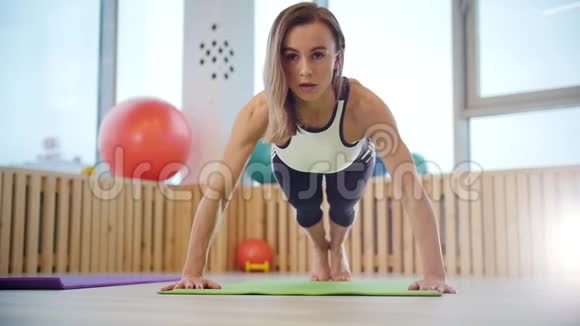 年轻女子健身教练在光明工作室做俯卧撑视频的预览图