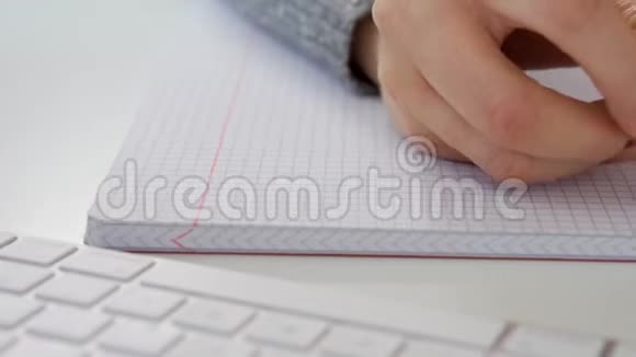 在白色电脑键盘旁边的笔记本上合上女性的手写便条视频的预览图