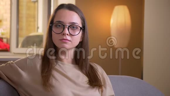戴着眼镜的年轻白种人女性的特写照片她开心地笑着看着坐在沙发上的摄像机视频的预览图