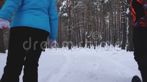 快乐的父母在冬天的松林里沿着白色的雪道骑着孩子在雪盘上女儿妈妈和爸爸视频的预览图