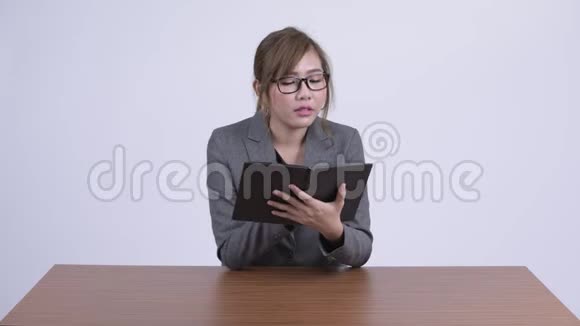 年轻快乐的亚洲女商人在书桌上看书视频的预览图