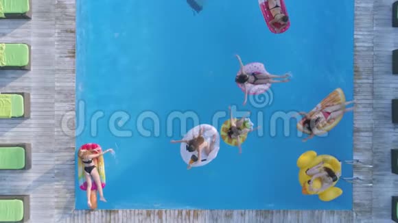 在昂贵的游泳池里在充气戒指和床垫上游泳与快乐的女性朋友在一起的无人机景视频的预览图