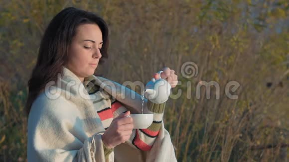 慢动作美丽的女人在河边的瓷茶壶浇绿茶视频的预览图