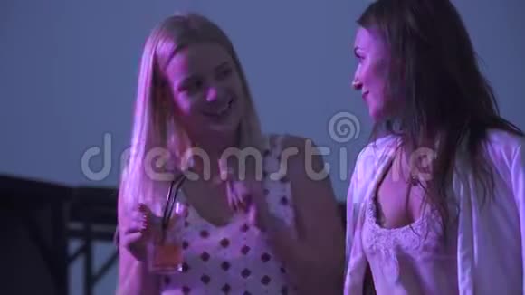 快乐的女朋友在夜总会喝鸡尾酒两个女孩正坐着喝鸡尾酒在夏天聊天视频的预览图