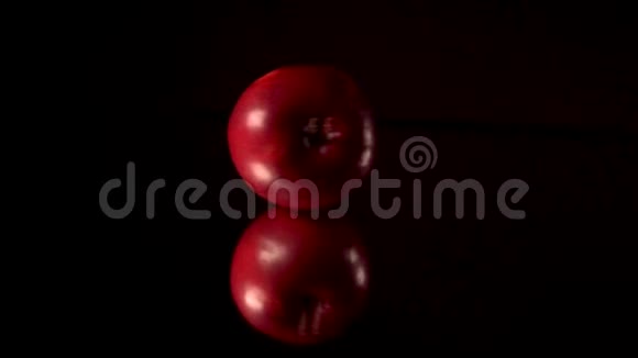 新鲜的红苹果在黑镜桌上旋转滚动黑色背景视频的预览图
