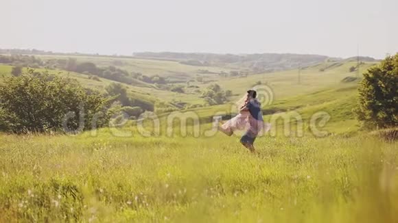 阳光明媚的一天一对年轻漂亮的夫妇在一片开阔的黄色田野里跳舞拥抱视频的预览图