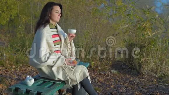黎明时分坐在长椅上喝茶的格子花呢美女视频的预览图