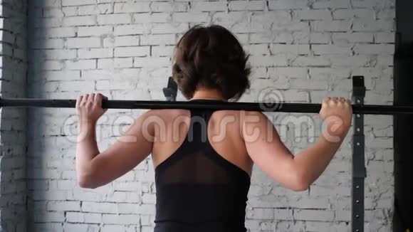 这段视频是关于美丽的年轻运动女性做背部蹲式有氧运动在健身房后近景视频的预览图