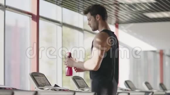 运动员在跑步机上的有氧训练中饮水视频的预览图