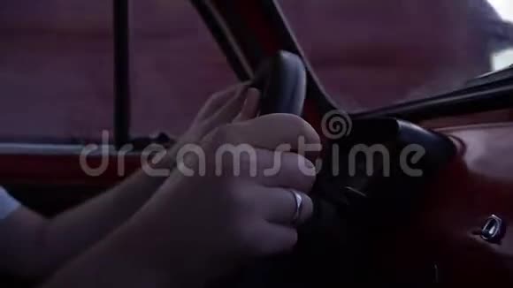 男子双手在小红色复古车的车轮上行驶在道路上近距离拍摄视频的预览图
