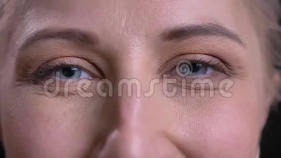 特写肖像美丽的中年女性灰色的眼睛看着镜头带着微笑的面部表情视频的预览图
