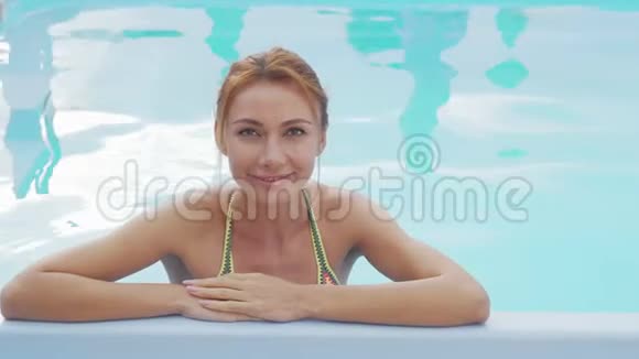 美丽快乐的女人微笑着在游泳池里放松视频的预览图
