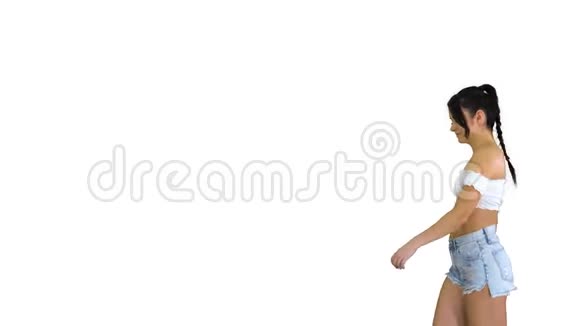 可爱的西班牙裔女性模特穿着牛仔短裤在白色背景下跳舞视频的预览图