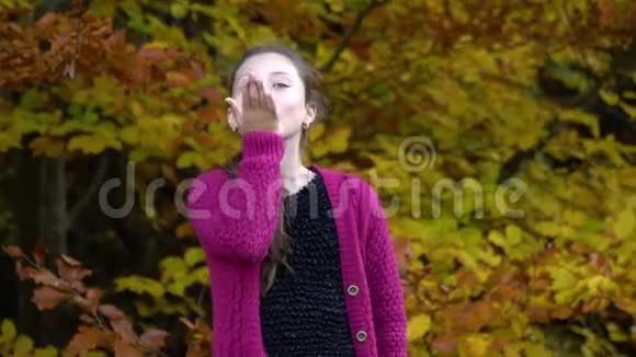 年轻漂亮的女孩走在秋天的森林里她高兴女孩给相机送了个吻视频的预览图