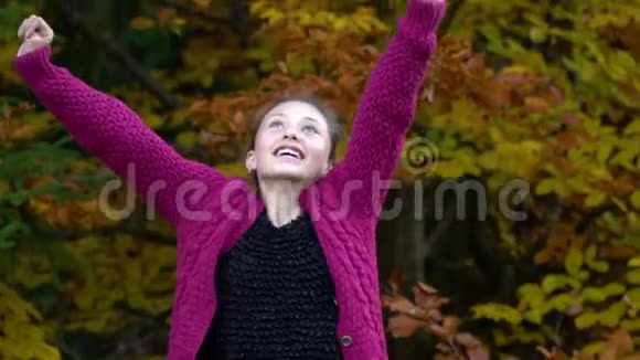 年轻漂亮的女孩走在秋天的森林里她高兴女孩看着相机微笑着视频的预览图