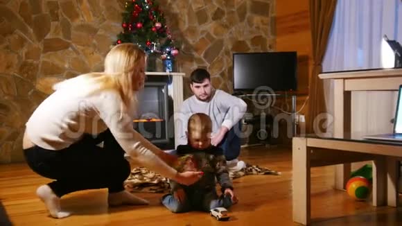 年轻幸福的家庭坐在舒适的房子里小男孩玩玩具汽车视频的预览图