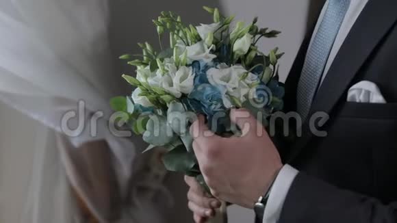 家里手里拿着结婚花束的新郎白色衬衫蓝色领带夹克视频的预览图
