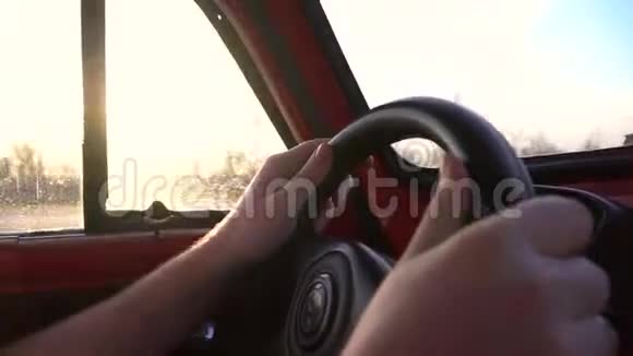 男子双手在小红色复古车的车轮上行驶在道路上近距离拍摄视频的预览图