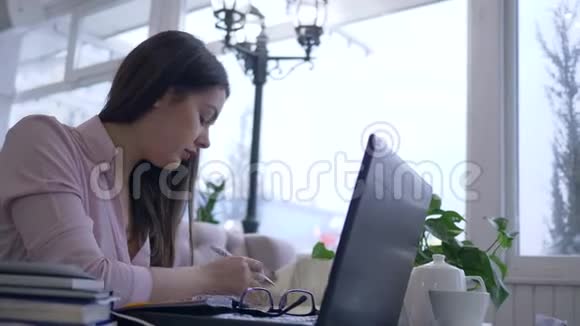 过度劳累的女学生利用现代计算机技术和书籍在远程在线课程学习视频的预览图