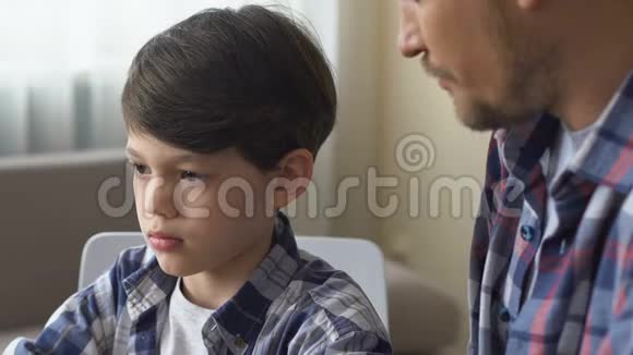 父亲训斥儿子强迫做家庭作业男孩看着父亲内疚特写视频的预览图