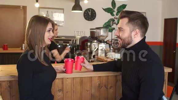 一对夫妇坐在一家咖啡店里喝着红杯咖啡视频的预览图