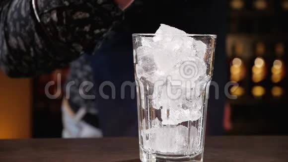 酒保用手把酒倒在杯子里的冰块上视频的预览图