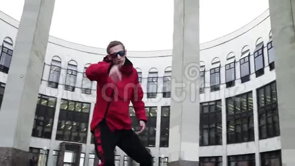 穿着红色运动服和太阳镜的帅哥就在花岗岩柱旁边视频的预览图
