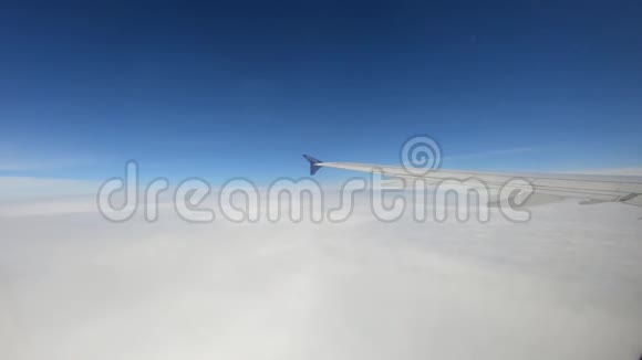 从一架飞机的窗户上看到高高地飞在雪白的云层上蓝色美丽的天空视频的预览图