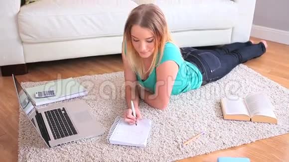 年轻漂亮的金发女郎在她的笔记本电脑上学习视频的预览图