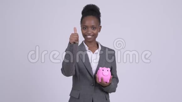 年轻快乐的非洲女商人拿着储蓄罐竖起大拇指视频的预览图