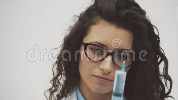 穿着白色医用长袍微笑的女医生或护士的肖像手中的一种注射器隔离在一个视频的预览图
